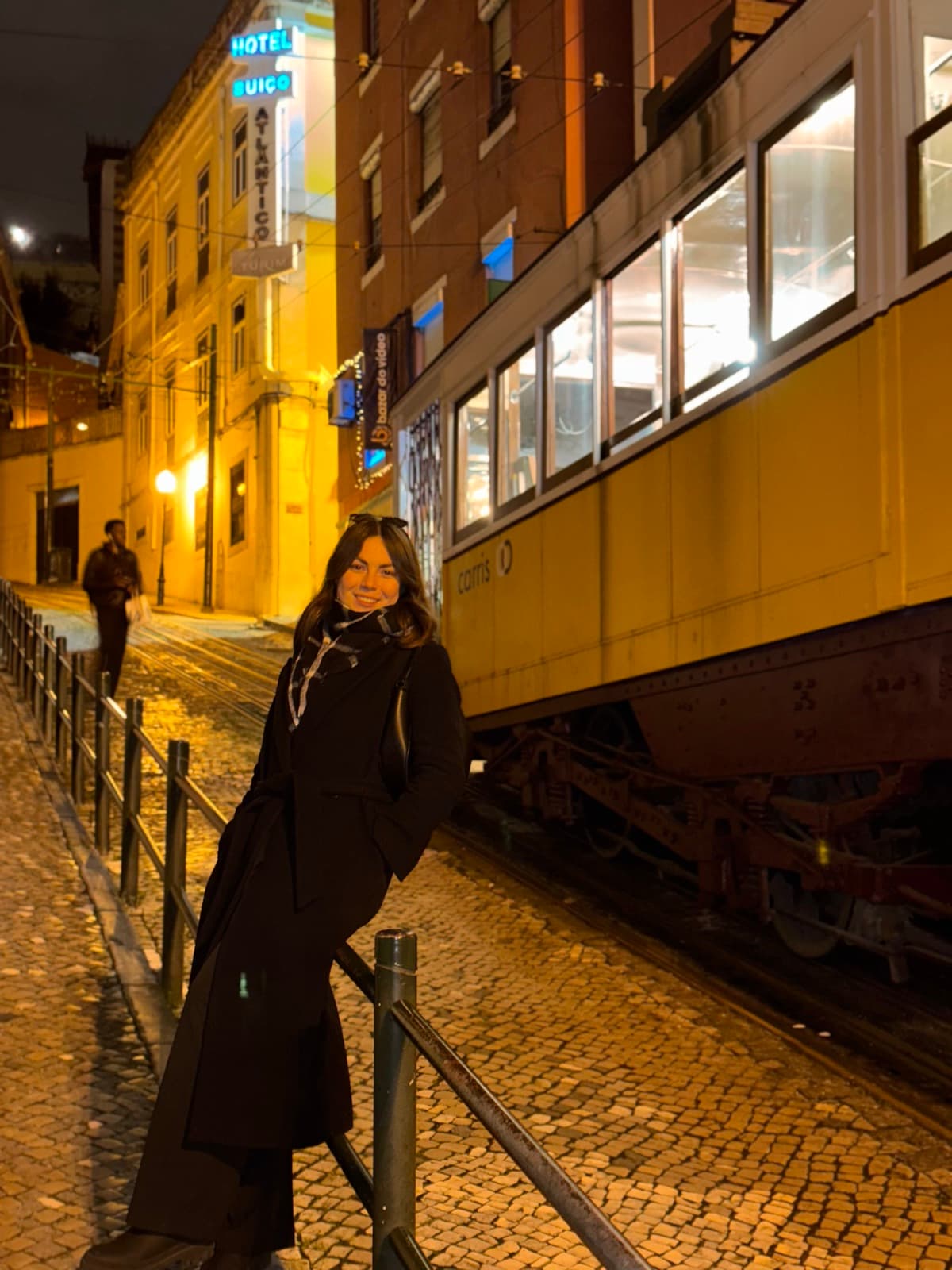 Karolina next to a yellow Lisbon tram at night
